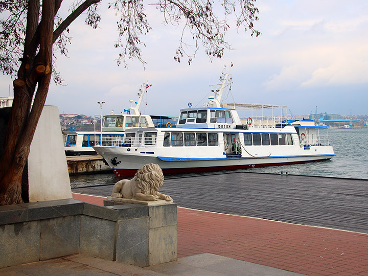 Пассажирский катер "Фотон" и скульптура льва на Графской пристани Севастополя